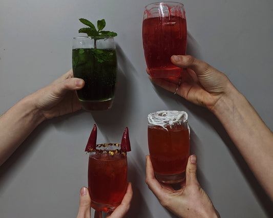 All About Kombucha presents four handcrafted kombucha mocktails — featuring a refreshing mint infusion, a vibrant berry fizz, a spicy devil-horn twist, and a creamy coconut-rimmed delight  held up in a celebratory cheers.