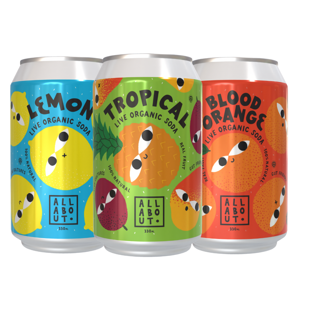 Three cans of All About Kombucha Live Soda in Lemon, Tropical, and Blood Orange flavours, featuring colourful fruit-themed designs.