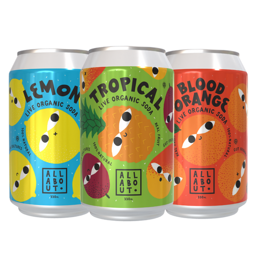 Three cans of All About Kombucha Live Soda in Lemon, Tropical, and Blood Orange flavours, featuring colourful fruit-themed designs.