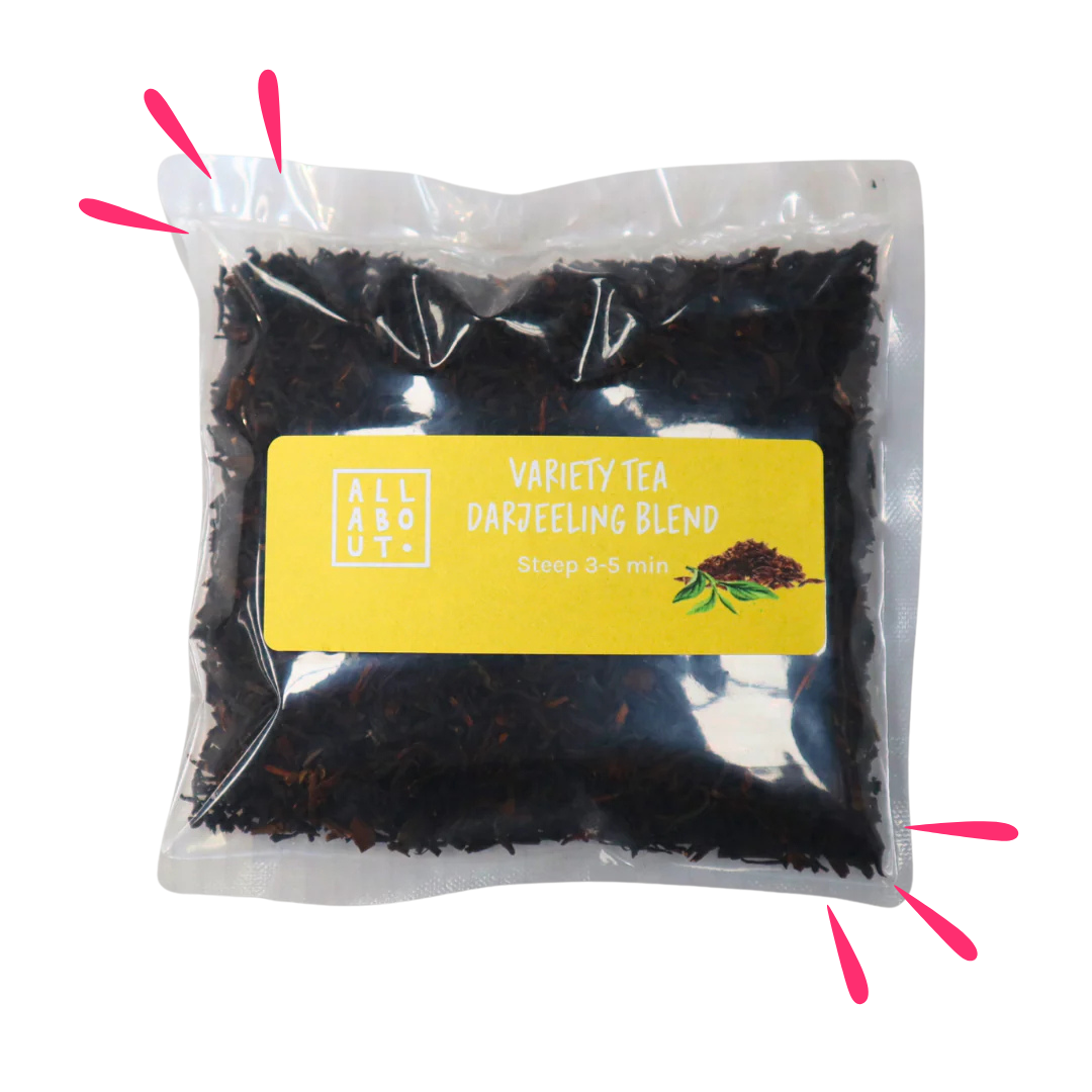 All About Kombucha variety tea pouch labeled Darjeeling Blend in a clear steeping pack with yellow label, filled with dark loose leaf tea and a tea leaf illustration.