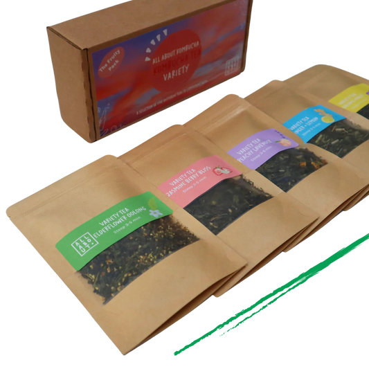 All About Kombucha tea variety pack featuring five kraft paper pouches of loose leaf tea blends, including elderflower oolong, berry bliss, and peach blossom, alongside branded packaging box.